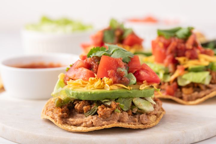 Ground Turkey Tostadas Ground turkey tostadas with refried beans, ground turkey, lettuce, tomato, avocado, and shredded cheese.