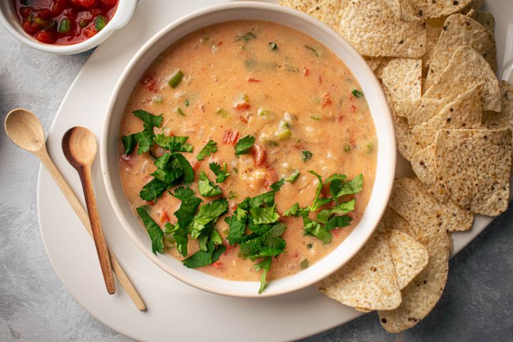 Healthy Queso Dip Healthy queso dip with melted cheddar cheese, diced tomatoes, and jalapeños in a bowl with tortilla chips.