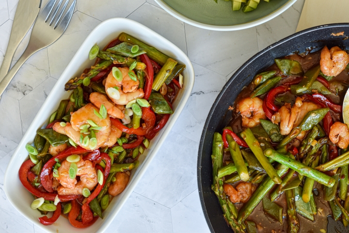 Honey Garlic Shrimp Stir Fry Honey garlic shrimp stir fry on a plate with asparagus, snap peas, red peppers, and stir fry sauce.