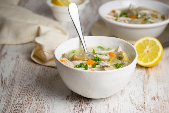 Lemon Chicken Artichoke Soup (Slow Cooker, Instant Pot, or Stovetop) Slow cooker lemon artichoke chicken soup with rice in a bowl with carrots and lemon.
