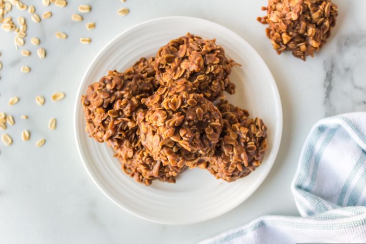 Healthy No Bake Oatmeal Cookies No bake peanut butter oatmeal cookies on a plate with loose oats on the side.