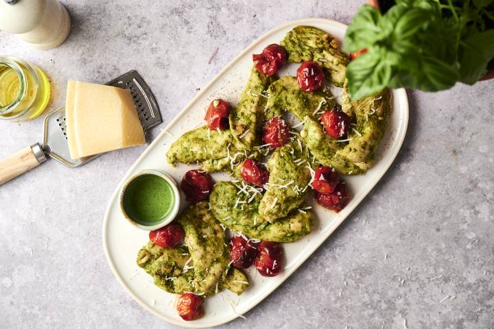 Pesto Chicken Juicy pesto chicken tenders topped with roasted cherry tomatoes and Parmesan cheese, served with extra pesto sauce on the side.