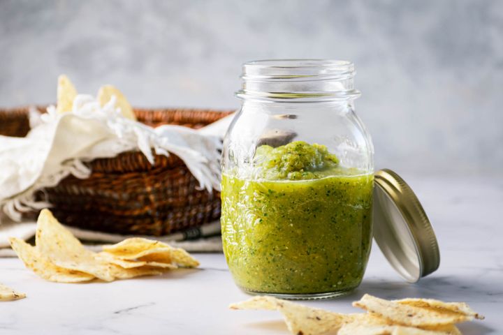 Salsa Verde Roasted salsa verde with tomatillos, jalapenos, and cilantro in a mason jar with chips on the side.