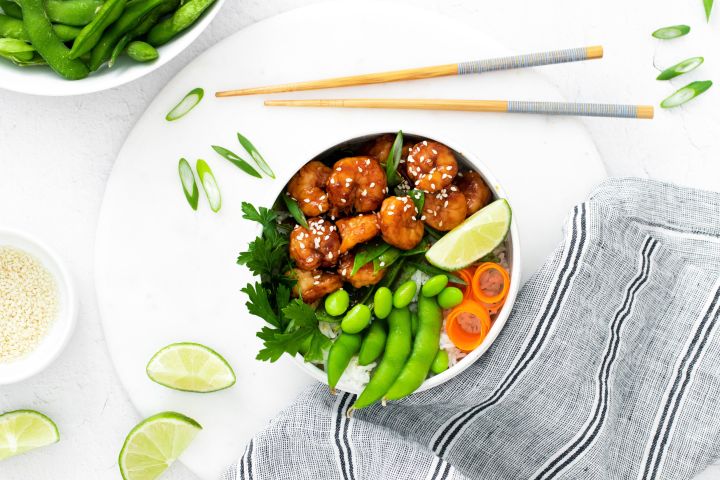 Sesame Shrimp Sesame shrimp in a bowl with white rice, edamame, snow peas, and carrots.