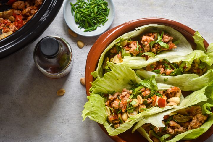 Slow Cooker Chicken Lettuce Wraps Slow cooker chicken lettuce wraps on a plate with lettuce leaves stuffed with chicken, mushrooms, peppers, and cilantro.