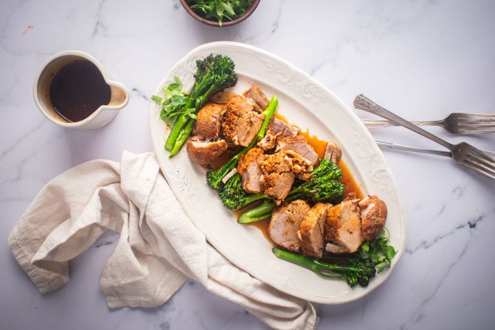 Slow Cooker Pork Tenderloin Slow cooker pork tenderloin with mustard sauce and broccolini on a white platter.