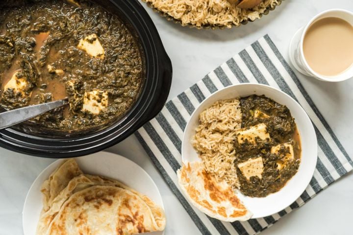 Slow Cooker Saag Paneer - Indian Spinach Slow cooker saag paneer on a plate with brown rice and Naan bread with the slow cooker on the side.
