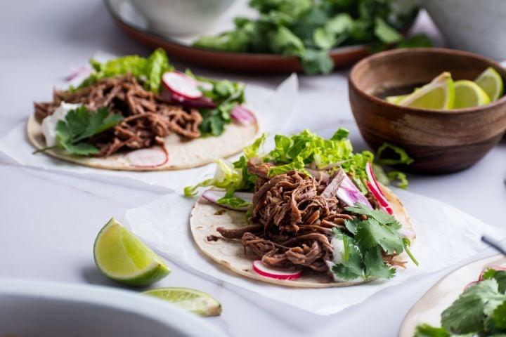 Slow Cooker Tri-Tip Tacos Slow cooker tri tip tacos on white corn tortillas with lettuce, cilantro, and radishes.