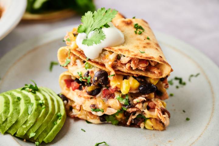 Spicy Chicken Quesadillas Spicy chicken quesadillas with shredded chicken, melted cheese, black beans, and corn in flour tortillas with sour cream, avocado, and cilantro.