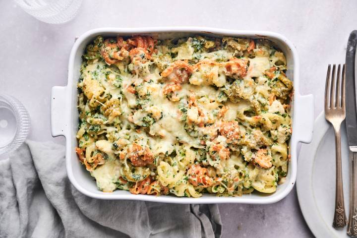 Spinach Artichoke Pasta Spinach artichoke pasta with melted cheese in a casserole dish.