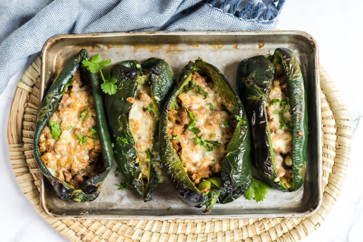 Stuffed Poblano Peppers Stuffed poblano peppers with ground turkey, melted cheese, and mozzarella on a baking sheet.