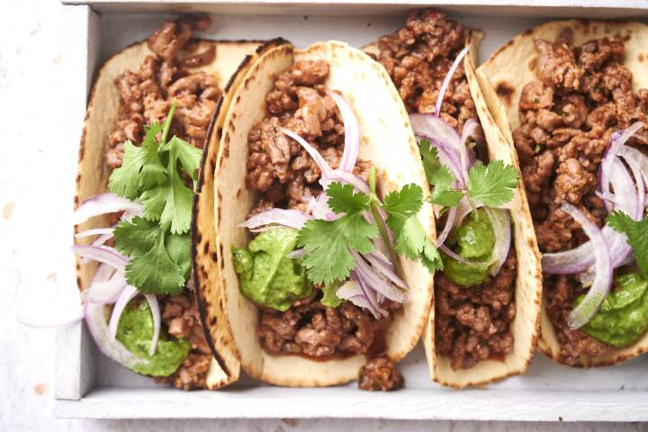 Quick and Easy Taco Meat Taco meat served in crispy tortillas with cilantor, onions, and guacamole.