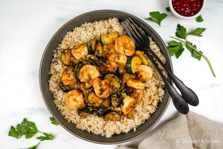 Thai Basil Shrimp Stir Fry Thia baisl shrimp stir fry with zucchini, cooked shrimp, and brown rice in a bowl.