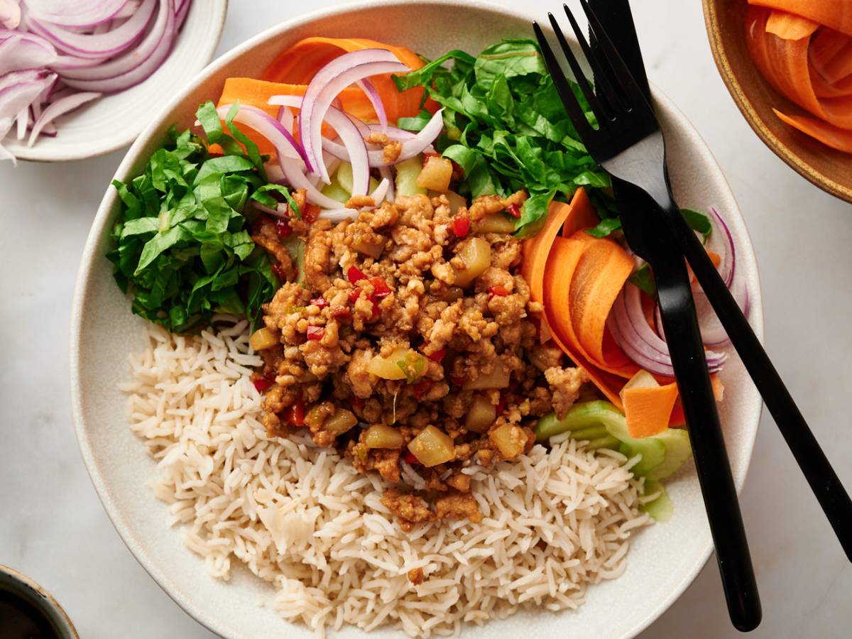 High-Protein Turkey Asian ground turkey bowls with lean ground turkey, bell peppers, mushrooms, and water chestnuts served with rice, carrots, cucumbers, lettuce, and green onions.