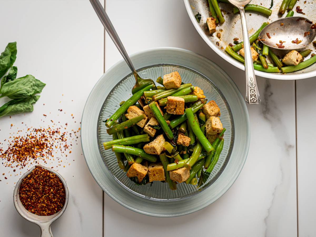 Vegetarian Dinner Ideas Basil tofu with green beans in a glass bowl with a skillet on the side.