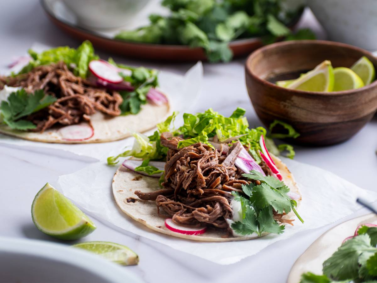 Slow Cooker Dinner Recipes Slow cooker tri tip tacos on white corn tortillas with lettuce, cilantro, and radishes.