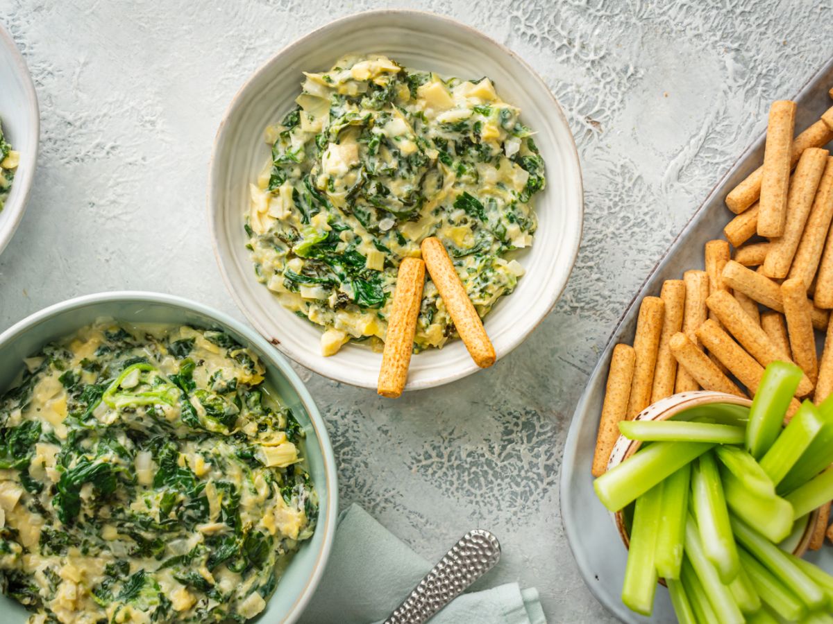Vegetarian Slow Cooker Recipes Slow cooker spinach artichoke dip with kale in three bowls with celery and breadsticks.