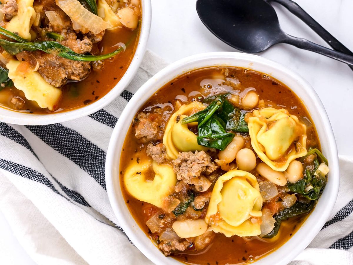 Slow Cooker Italian Recipes Spinach tortellini soup in a bowl with ground turkey, spinach, white beans, and tomatoes in a white bowl.