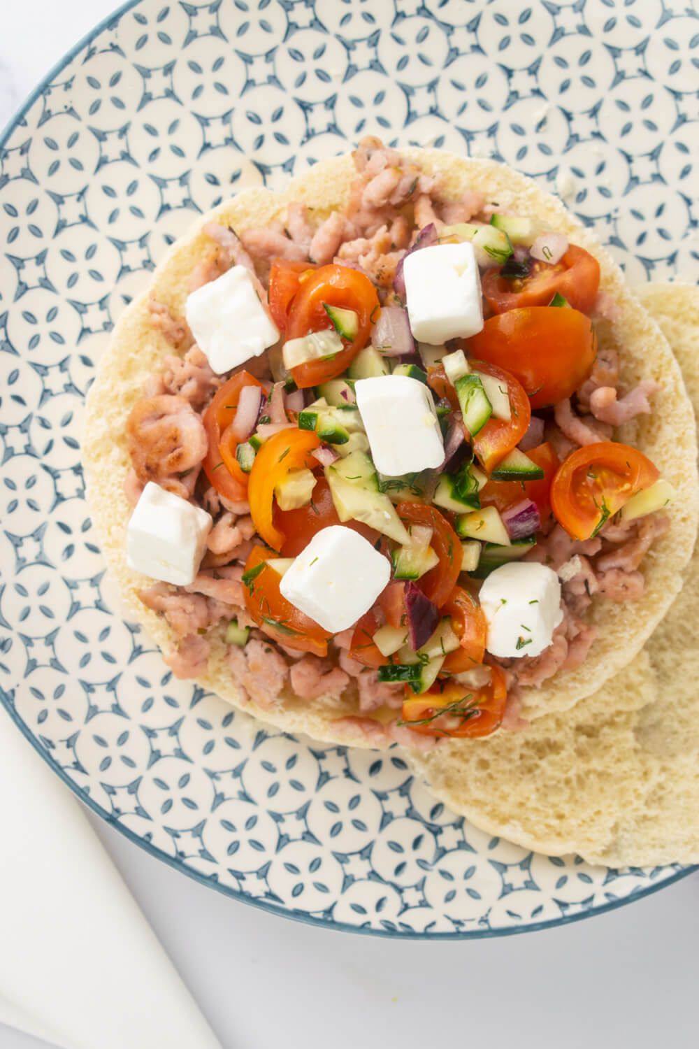 Turkey Tostadas with Greek salad and feta cheese on pita bread.