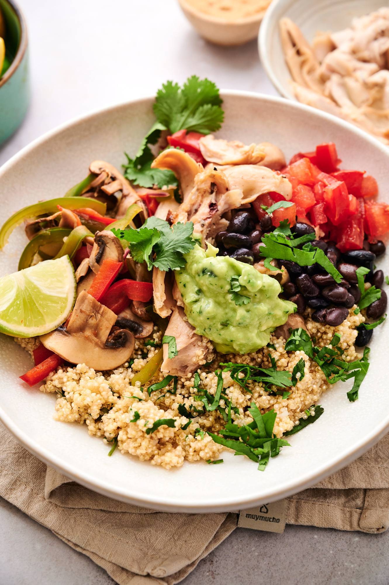 Leftover rotisserie chicken bowls served with cilantro quinoa, black beans, peppers, onions, mushrooms, and guacamole.