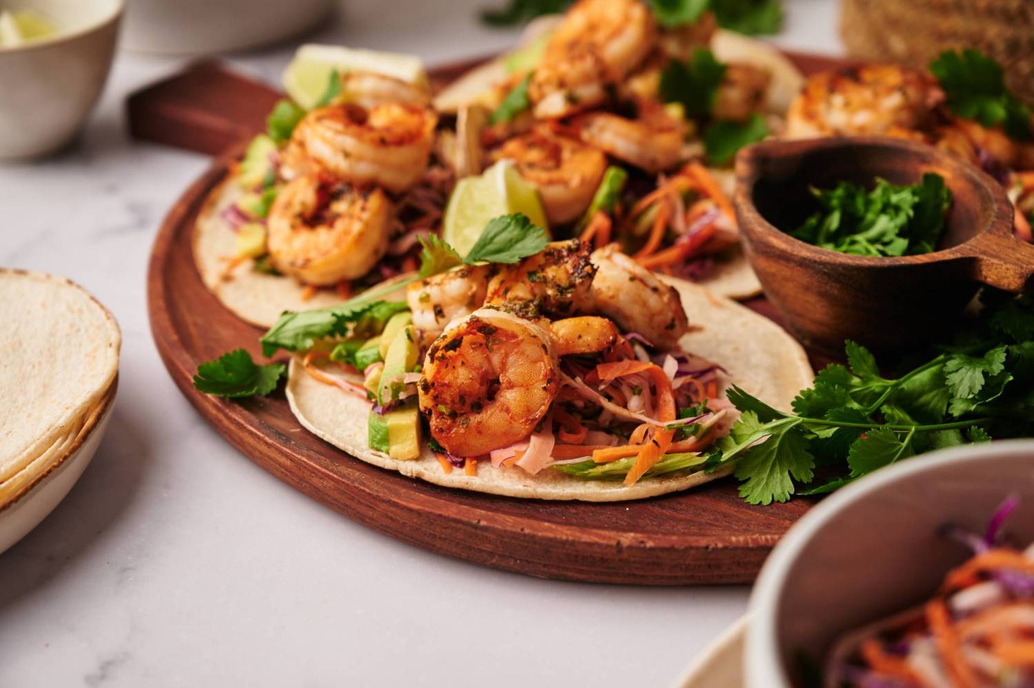 Mexican shrimp tacos with cabbage lime slaw served in corn tortillas with avocado and cilantro.