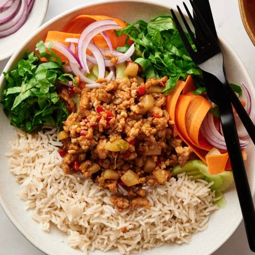 Asian ground turkey bowls with lean ground turkey, bell peppers, mushrooms, and water chestnuts served with rice, carrots, cucumbers, lettuce, and green onions.