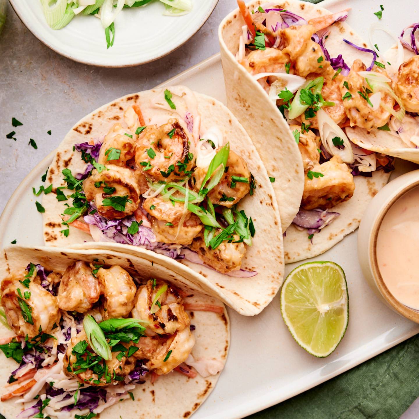 Bang bang shrimp tacos with creamy coleslaw, cilantro, green onions, and crispy shrimp in corn tortillas.