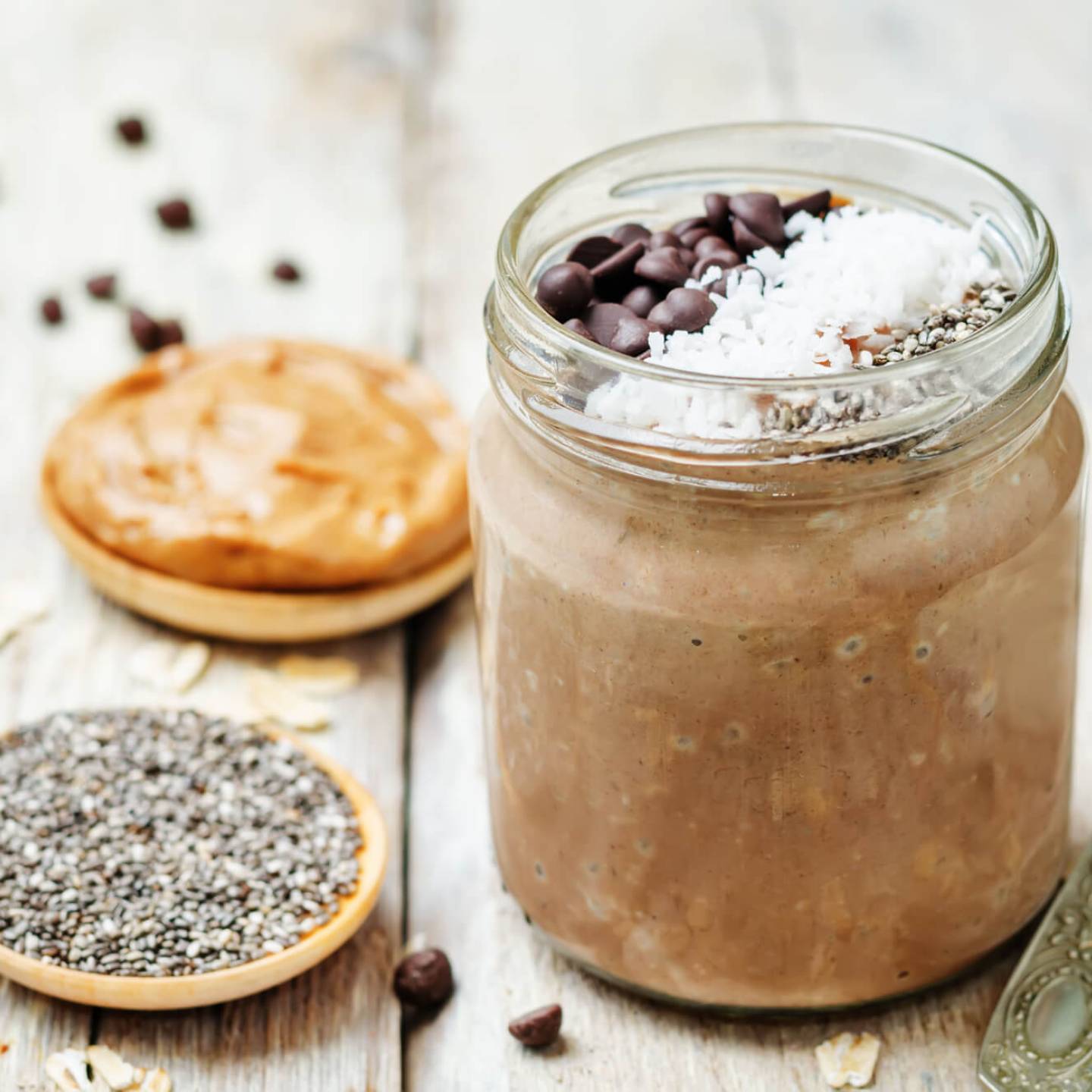 Chocolate peanut butter chia seed pudding served in a glass jar with peanut butter and chia seeds on the side.