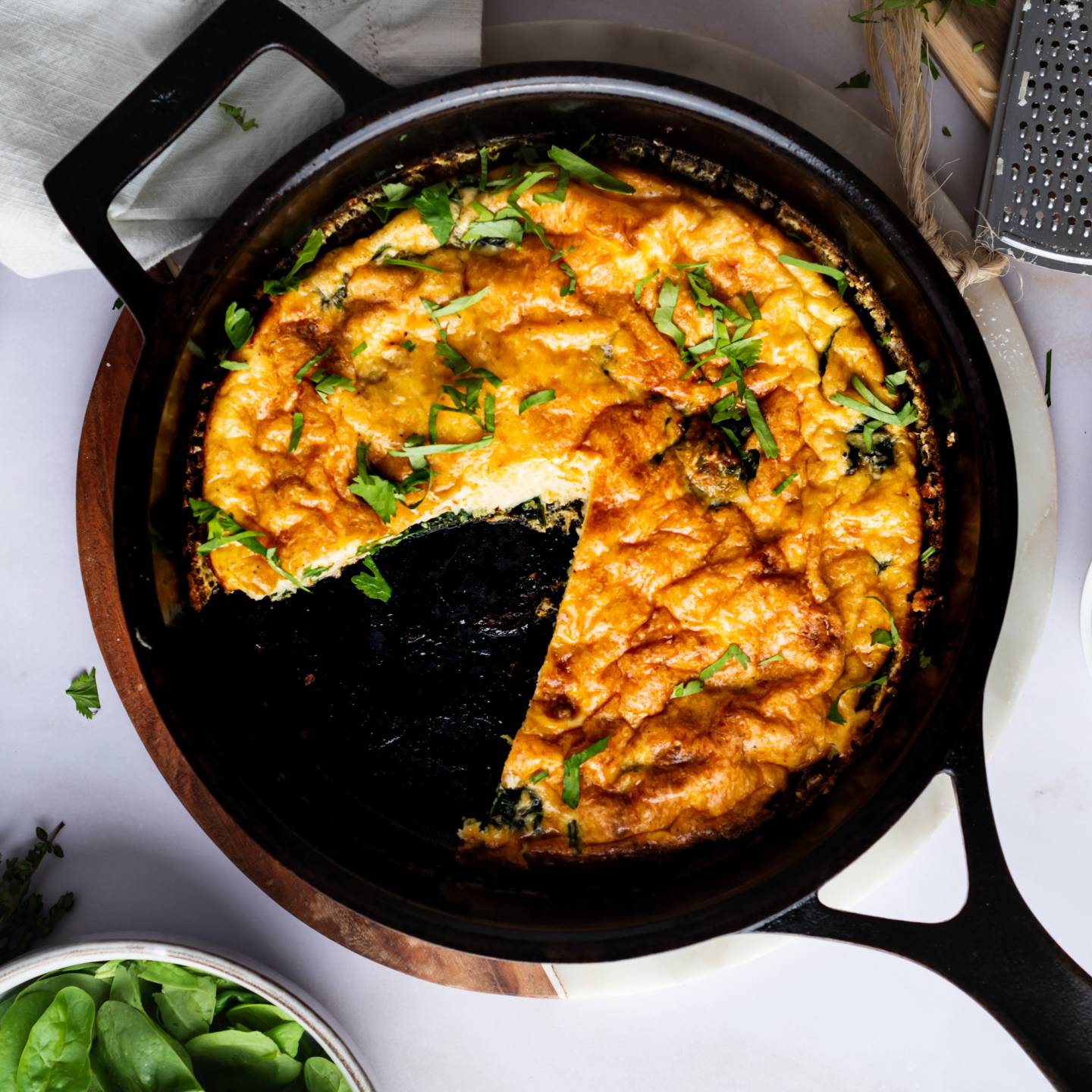 Spinach frittata with cheddar and Parmesan cheese in a cast iron skillet.