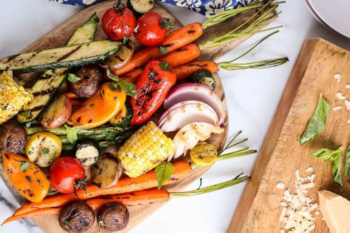 Grilled vegetable skewers seen from above on a beautiful round plate pictured on a marble top table. 