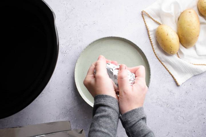 Potatoes being wrapped in foil.
