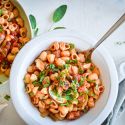 Sausage and pepper pasta with turkey sausage, bell peppers, onions, mushrooms, and tomato sauce in two bowls with garlic.