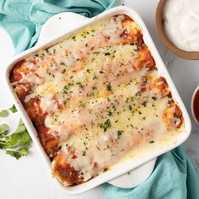overhead shot of a small batch of chicken enchiladas in a baking dish.