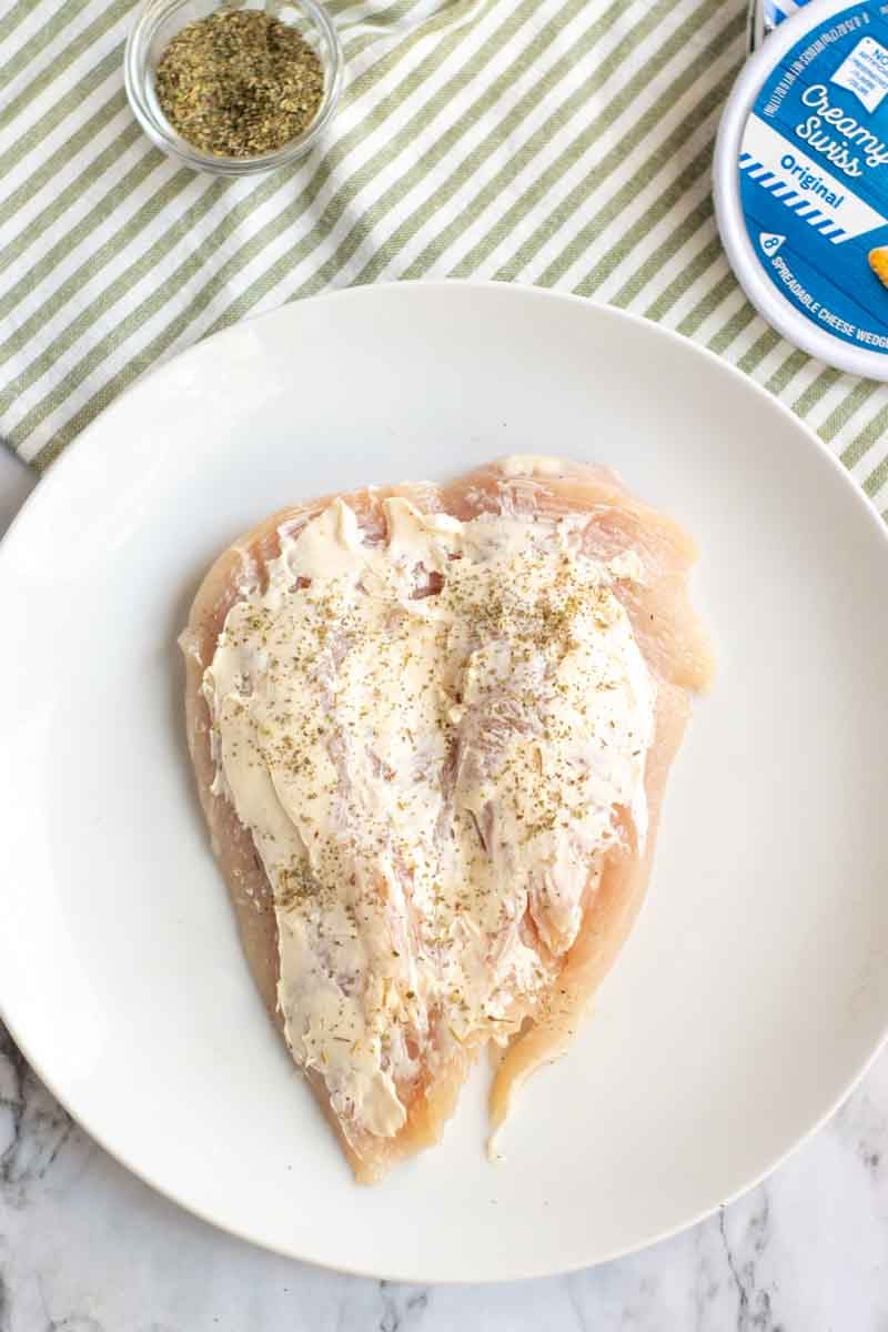 Butteflied chicken breast on a white plate spread with Laughing Cow cheese and sprinkled with Italian seasoning Laughing Cow Chicken is a lightened up version of a stuffed chicken breast. This super easy, 5 ingredient dinner will please your picky eaters and wow your foodies. | www.persnicketyplates.com