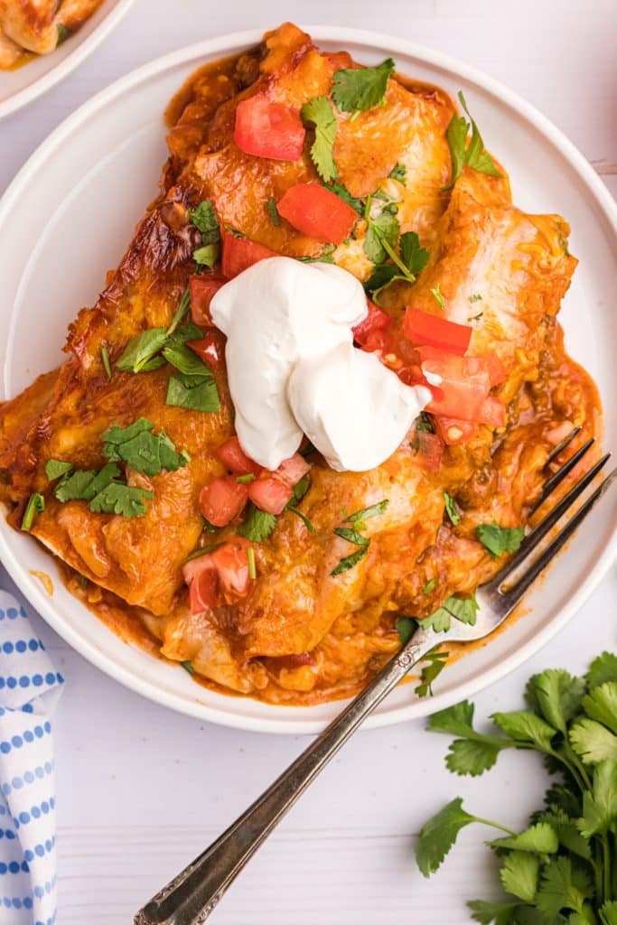 enchiladas topped with sour cream & cilantro on a plate.