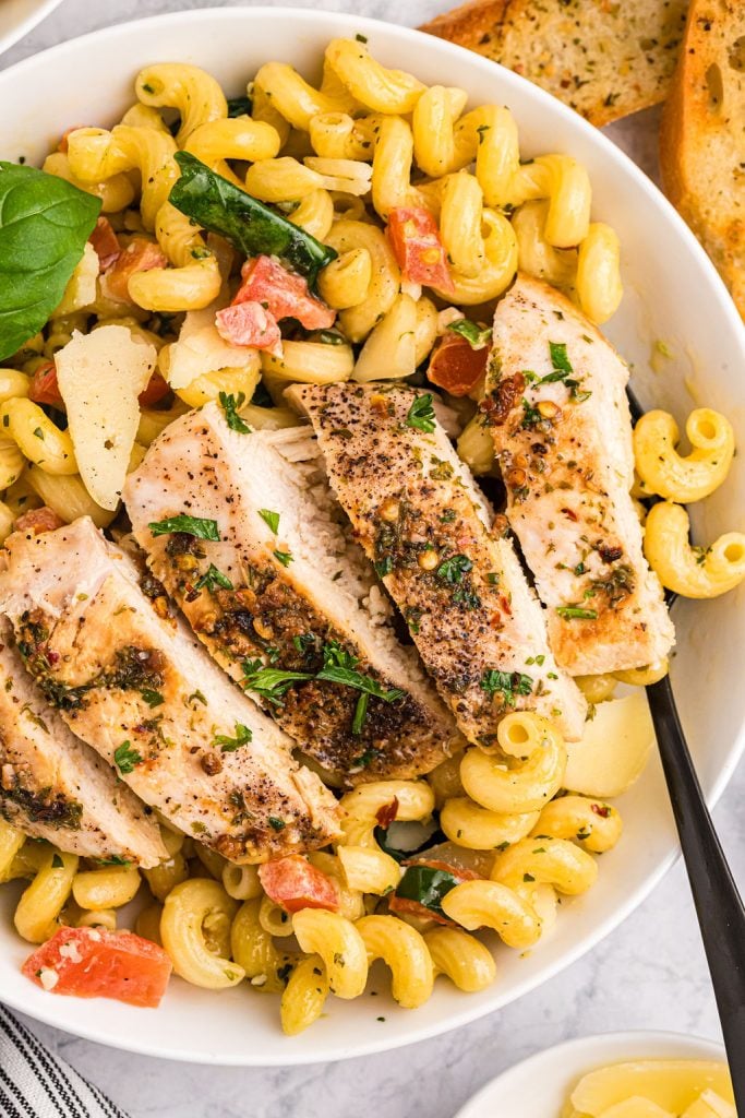 sliced grilled chicken breast on top of pesto cavatappi.