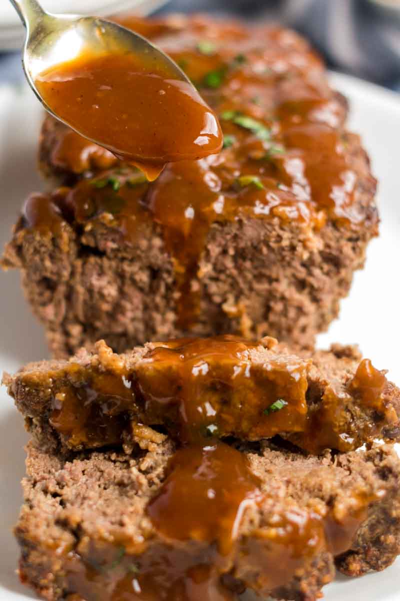 Classic Meatloaf with Brown Gravy for those nights you're feeling nostalgic and want an easy, filling meal. | www.persnicketyplates.com sliced meatloaf with brown gravy pouring over top