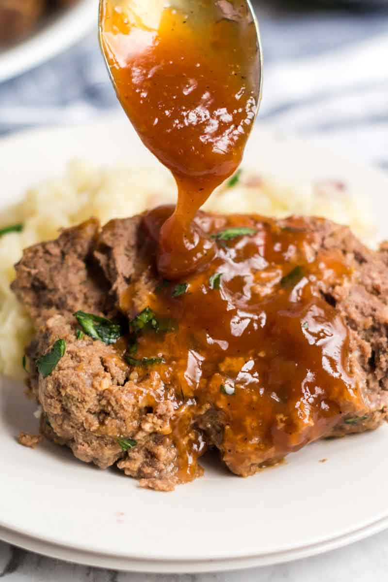 Classic Meatloaf with Brown Gravy for those nights you're feeling nostalgic and want an easy, filling meal. | www.persnicketyplates.com slice of meatloaf with brown gravy being spooned over top