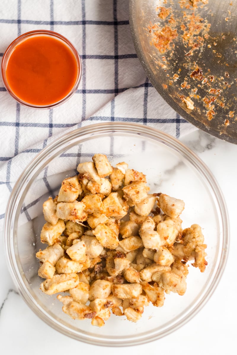 bowl of chicken with wing sauce for buffalo ranch chicken wraps