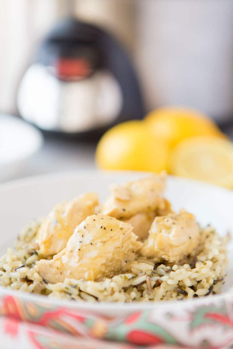 lemon chicken on a bed of rice with slow cooker & lemons in background