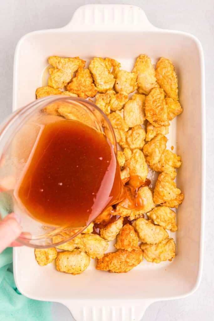 sweet & sour sauce pouring over chicken chunks.