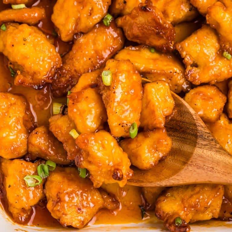 wooden spoon lifting a scoop of sweet & sour chicken.