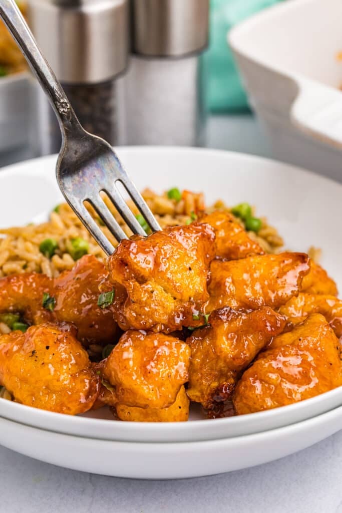 fork poking into a chunk of sweet & sour chicken.