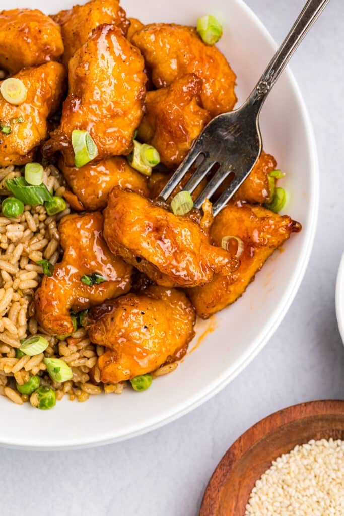fork poking into a chunk of sweet & sour chicken.