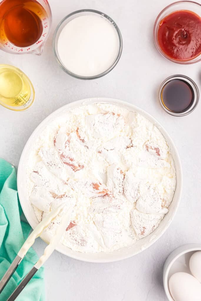 chicken pieces being dredged in cornstarch.