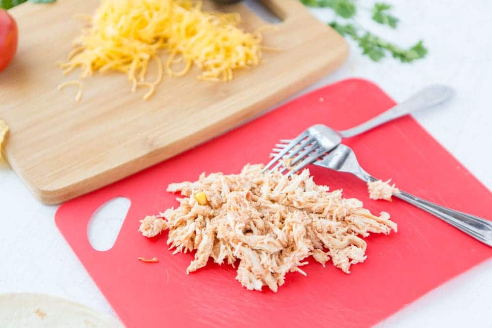 shredded chicken on cutting board for slow cooker salsa chicken Three ingredient Crock Pot Salsa Chicken is in my regular dinner rotation because it's so easy & so good! Flavorful and versatile, this crockpot chicken breast recipe can be made into burritos, taco bowls, nachos, whatever you feel like! | www.persnicketyplates.com