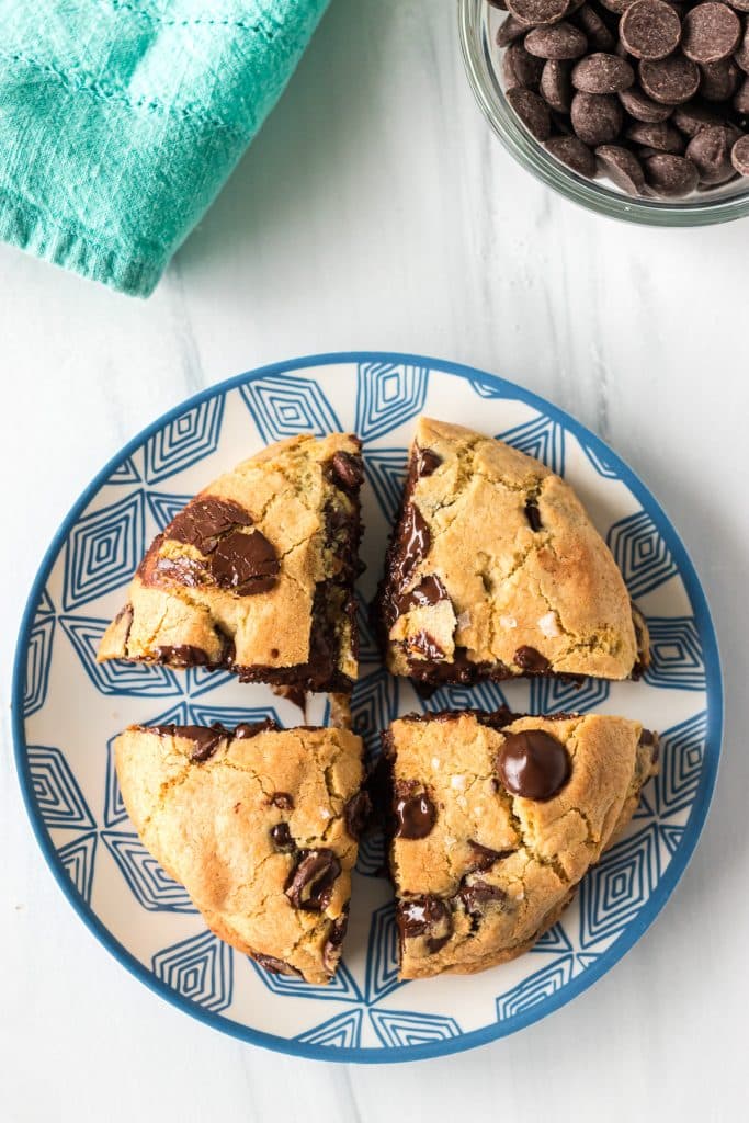 overhead shot of a giant cookie sliced into 4 pieces on a plate.