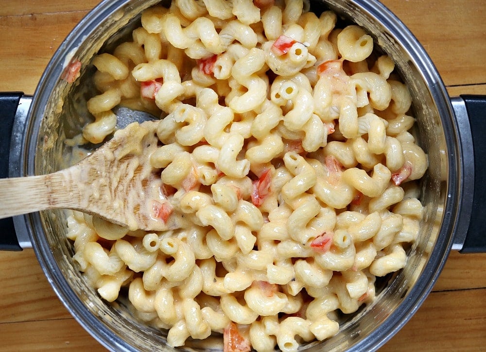 cheesy pasta in a saucepan with wooden spoon