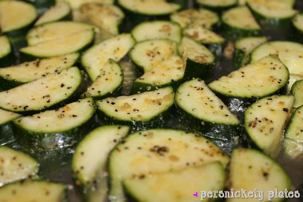 closeup of raw seasoned zucchini on baking sheet