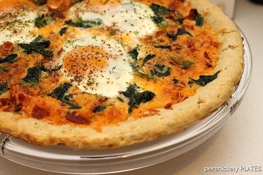 Bacon & spinach breakfast pizza is a filling and unique way to start your day. Pizza for breakfast is always a good idea! | www.persnicketyplates.com #pizza #breakfast #breakfastpizza #easyrecipe breakfast pizza on stand